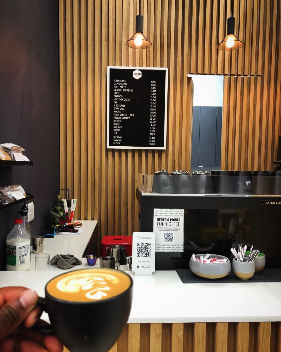 A freshly poured coffee in front of the Arise & Grind indoor coffee counter